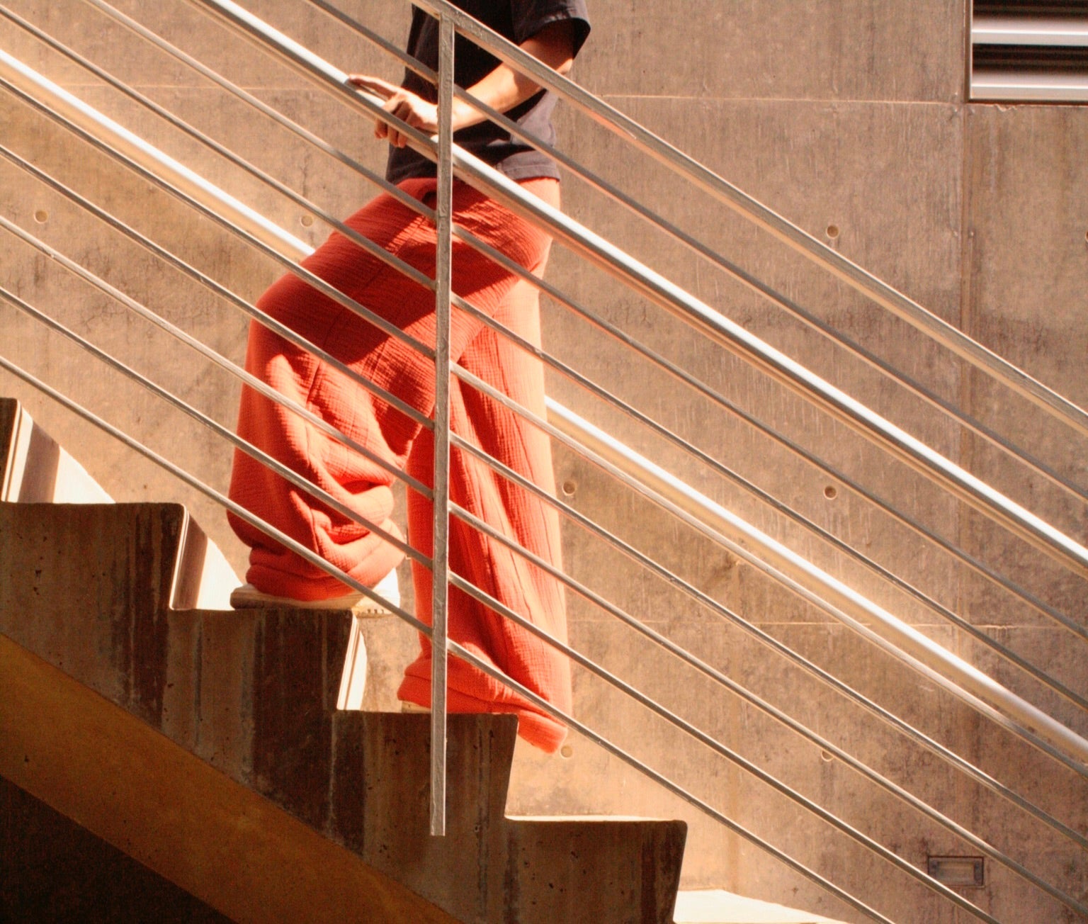 Model walking up stairs wearing Mariloulou Blanket Pants in Pink
