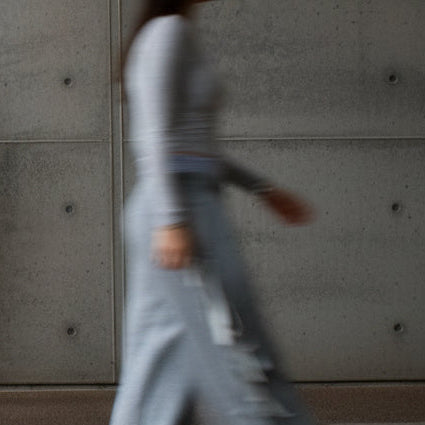 Person wearing a pink tracksuit standing between two blurred figures in an urban setting.