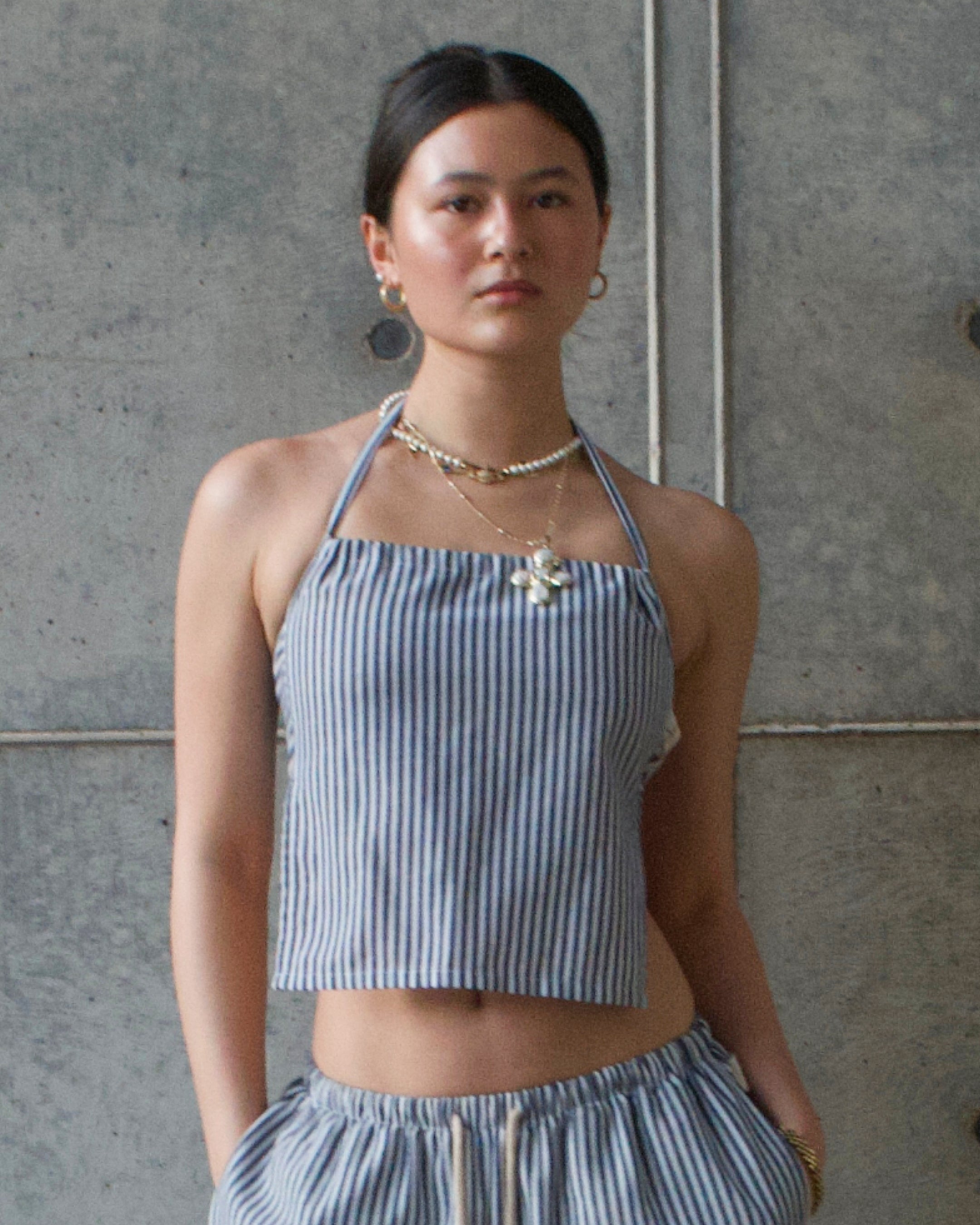 Woman wearing a blue and white striped outfit against a gray wall